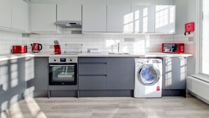 A modern kitchen with a built-in oven, microwave, and washing machine. - Roomspace Apartments - Brewers Lane (Richmond)
