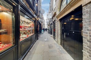 A narrow street lined with shops, including a jewelry store with glass display cases. - Roomspace Apartments - Brewers Lane (Richmond)
