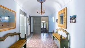 Un couloir doté d’un sol à motifs, d’un lustre et de deux miroirs richement décorés.