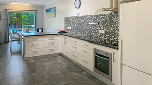 Une cuisine moderne avec des meubles blancs, un pare-feu en carrelage et un four encastré.