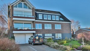 Een huis met twee verdiepingen, een garage, een oprit en een tuin.