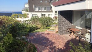 Een modern huis met een terras, een eethoek en uitzicht op zee.