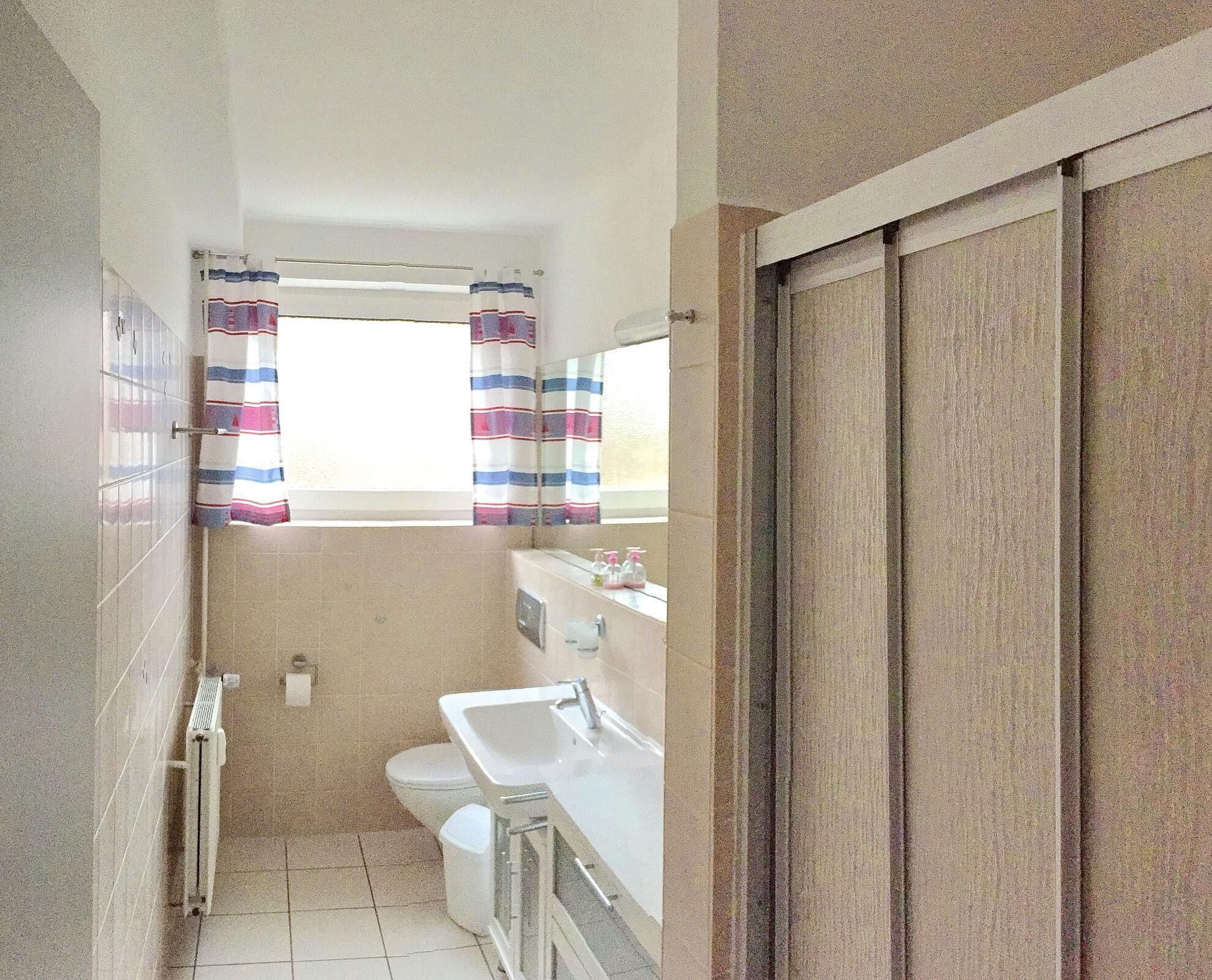 A small bathroom with a toilet, sink, and a window with striped curtains.