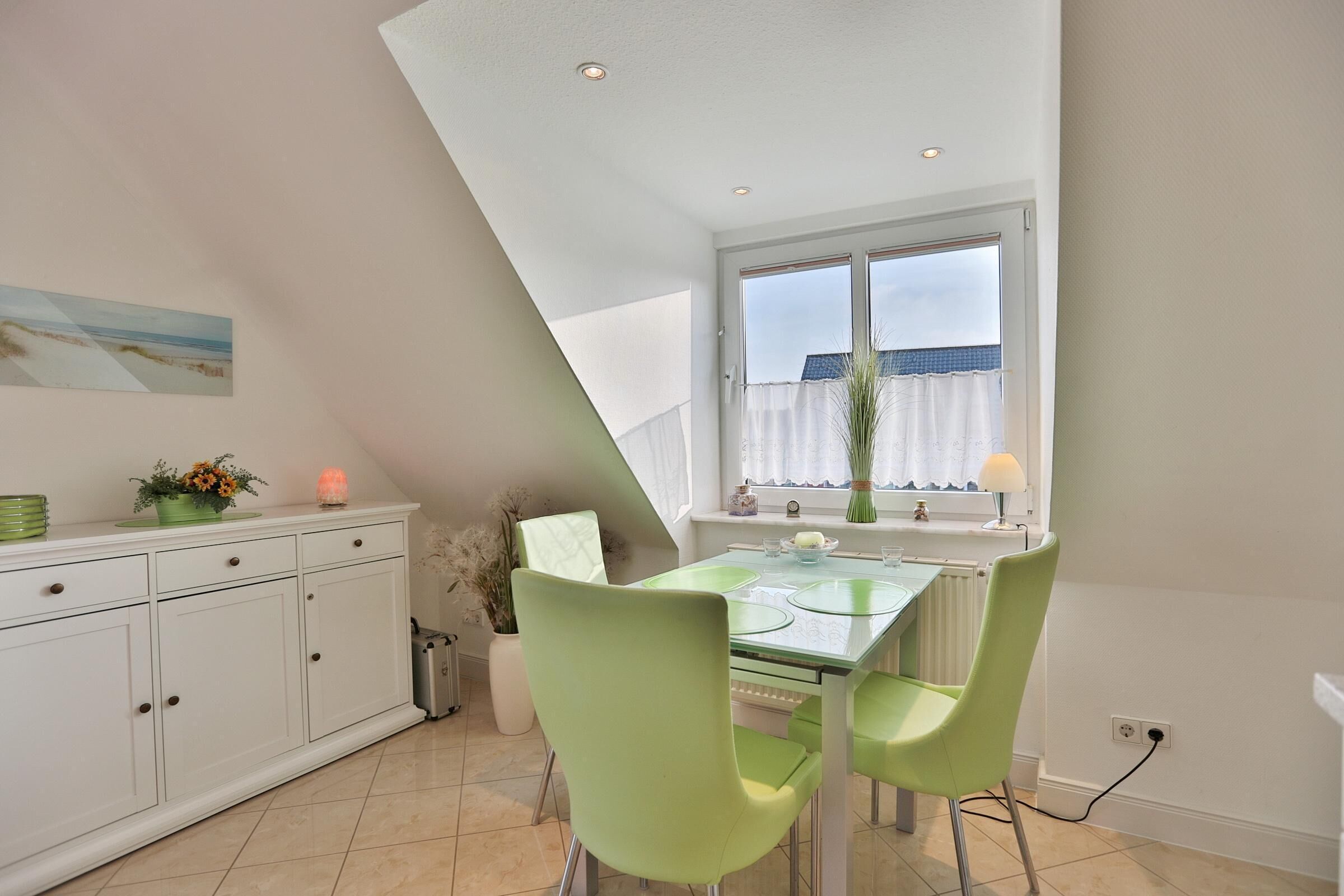 A dining area with a table, chairs, and a window with curtains.