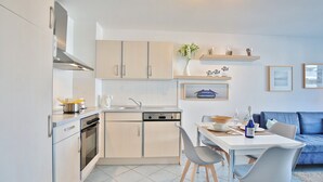 Eine moderne Küche mit Geschirrspüler, Backofen und Essbereich mit Tisch und Stühlen.