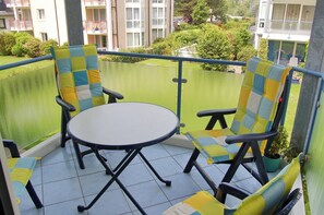 A balcony with two chairs and a table, surrounded by a green railing. - Hansa-residenz II Appartement 12 (Scharbeutz)