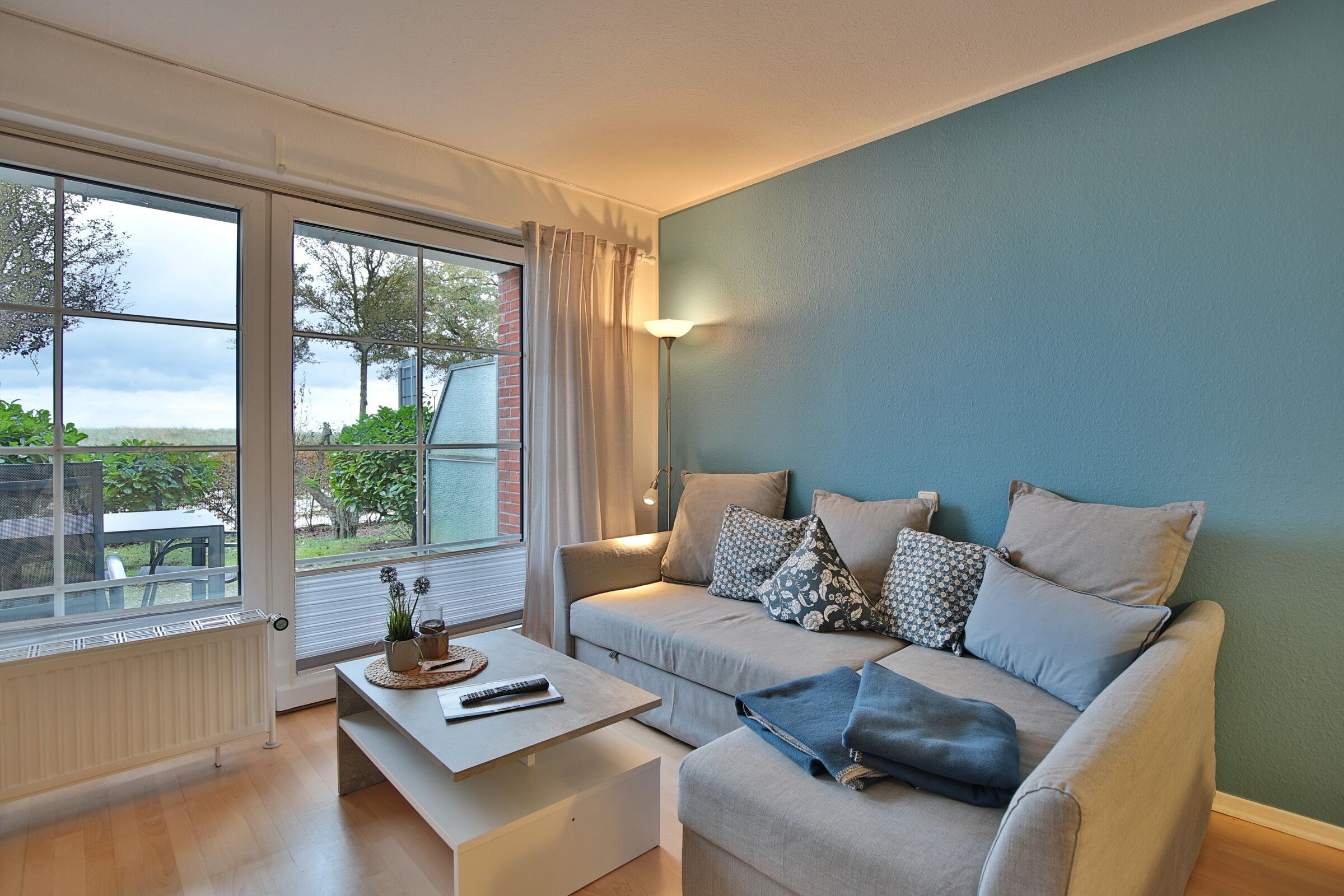 A modern living room with a sofa, coffee table, and large windows.