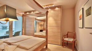 Ein Schlafzimmer mit Baldachinbett, einem Holzschrank und einem Sessel.