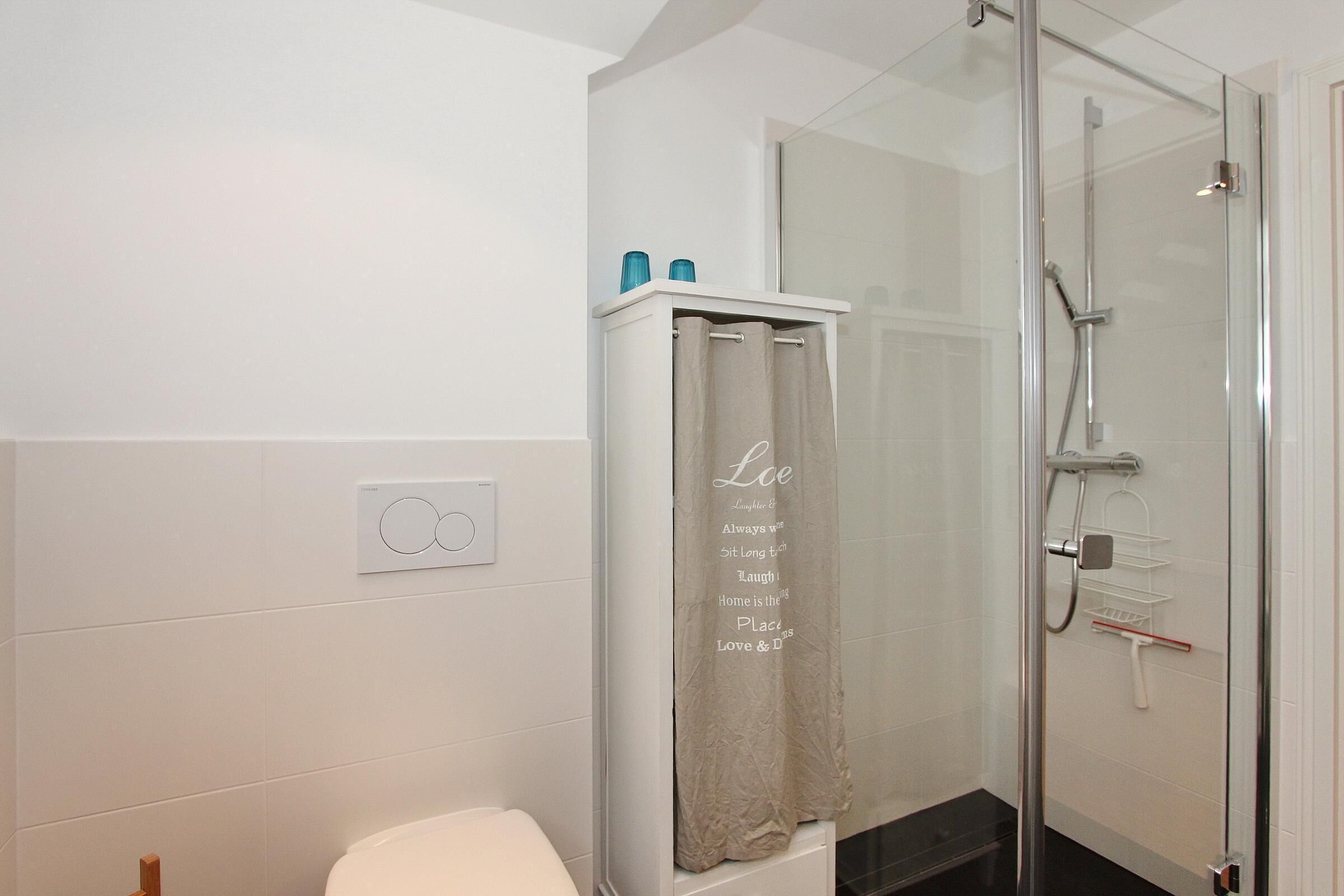 Un baño con ducha de vidrio, inodoro y toallero con una toalla.