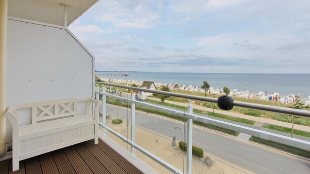 A balcony with a wooden floor, white railing, and a white bench. - Meerglück Appartement 5 (Haffkrug)