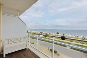 A balcony with a wooden floor, white railing, and a white bench. - Meerglück Appartement 5 (Haffkrug)