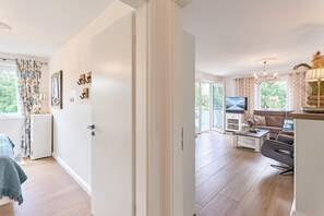 A modern living room with a sofa, coffee table, and TV. - Dünenhaus 3 Appartement 7 (Scharbeutz)