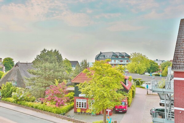 A residential area with a thatched-roof house, a red house with a garden, and a modern building with a red roof. - Haus Meeresbrise Appartement 18 (Haffkrug)