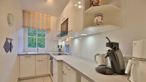 Una cucina moderna con mobili bianchi, una macchina da caffè e una finestra con tenda a righe.