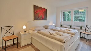 Una camera da letto con un letto grande, comodini, una sedia, una finestra con tende e un quadro appeso al muro.