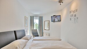 Een hotelkamer met een bed, een stoel, een televisie en een motiverende quote op de muur.