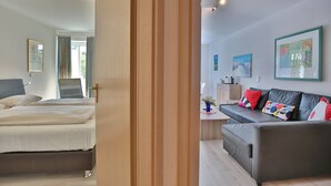 Een kamer met een bed, een bureau, een bank en een raam met gordijnen.