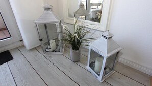 Nurkassa on kolme valkoista lyhtyä, yhdessä niistä on kasvi sisällä, ja peili heijastaa huonetta.