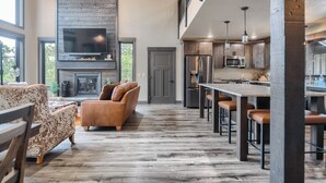 A modern kitchen with a large island, built-in appliances, and a stone fireplace. - New Spacious 3200 sq. ft. Cabin w/ Hot Tub Across Street from Clubhouse Pool (Lead)