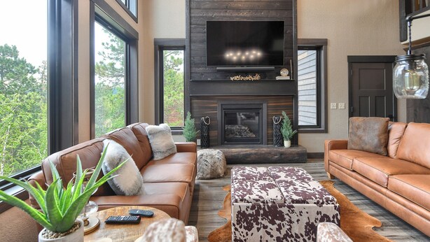 A modern living room with leather sofas, a fireplace, and a large TV. - New Spacious 3200 sq. ft. Cabin w/ Hot Tub Across Street from Clubhouse Pool (Lead)