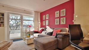 A modern living room with a sectional sofa, a coffee table, and a bookshelf. - Strandperle Appartement 203 (Haffkrug)