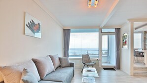 Ein modernes Wohnzimmer mit grauem Sofa, einem Couchtisch und Meerblick durch große Fenster.