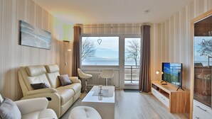 Een moderne woonkamer met een bank, fauteuils, een salontafel, een televisie en een groot raam met uitzicht.