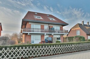 A two-story house with a balcony, a garage, and a well-maintained hedge. - Villa Meeresstrand Appartement 7 (Haffkrug)