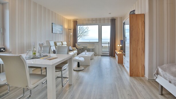 Een hotelkamer met een eethoek, een bank, een bijzettafeltje en uitzicht op zee.
