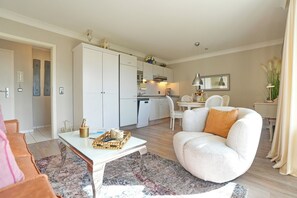 Uma sala de estar moderna com sofá, mesa de centro e área de jantar com cadeira e mesa.