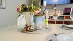 A table set with a bottle of wine, a glass, a menu, and a vase of flowers. - Strandschlösschen Appartement 28 (Haffkrug)