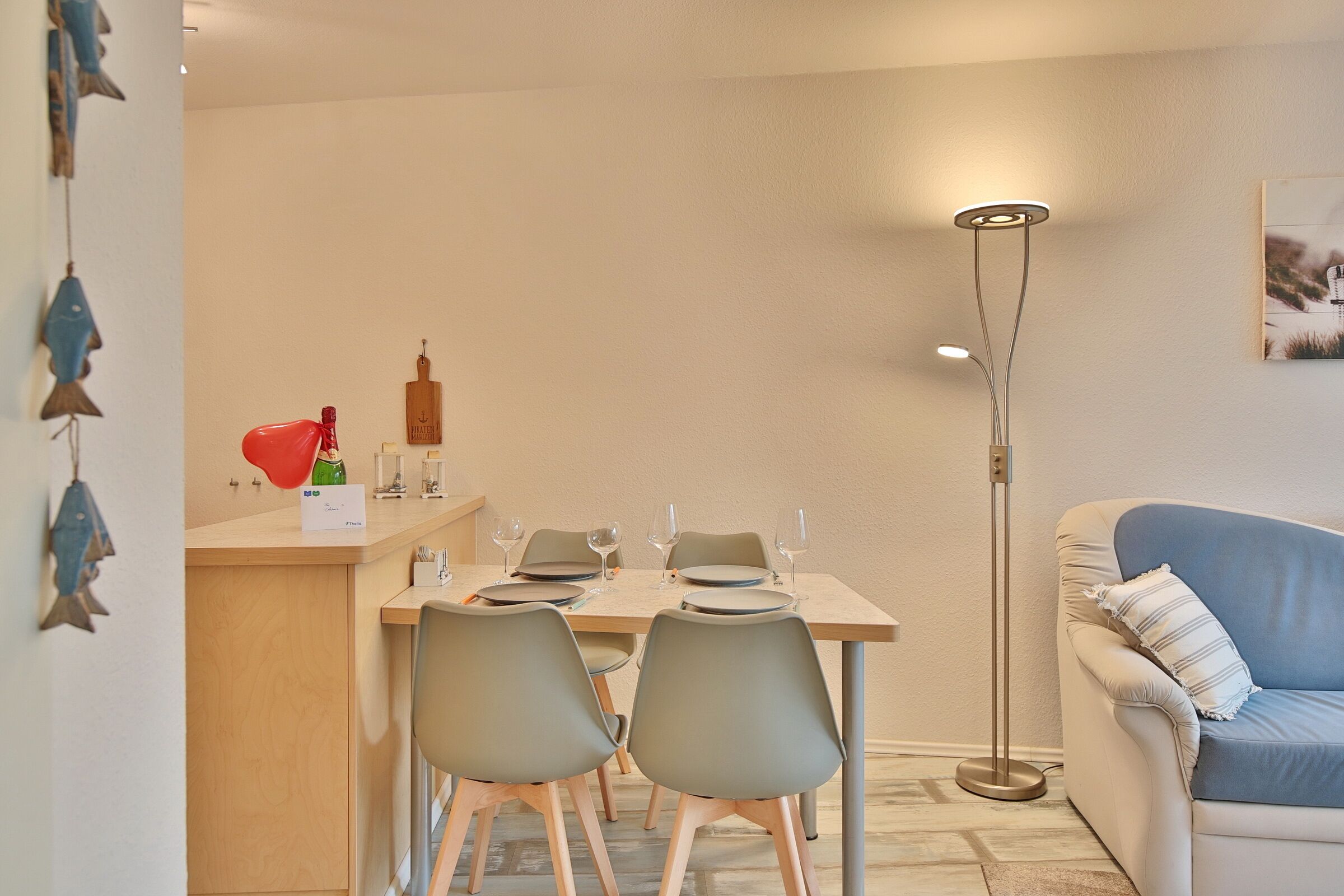 A dining area with a table set for four, a bar counter, and a sofa.