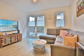 A modern living room with a large flat-screen TV, a sofa, a coffee table, and a vintage trunk as a cabinet. - Bude 30 Tilly Appartement 2 (Scharbeutz)