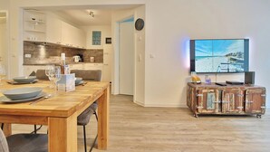 Una cocina moderna con armarios de madera, una mesa de comedor para cuatro personas y un televisor montado en la pared.