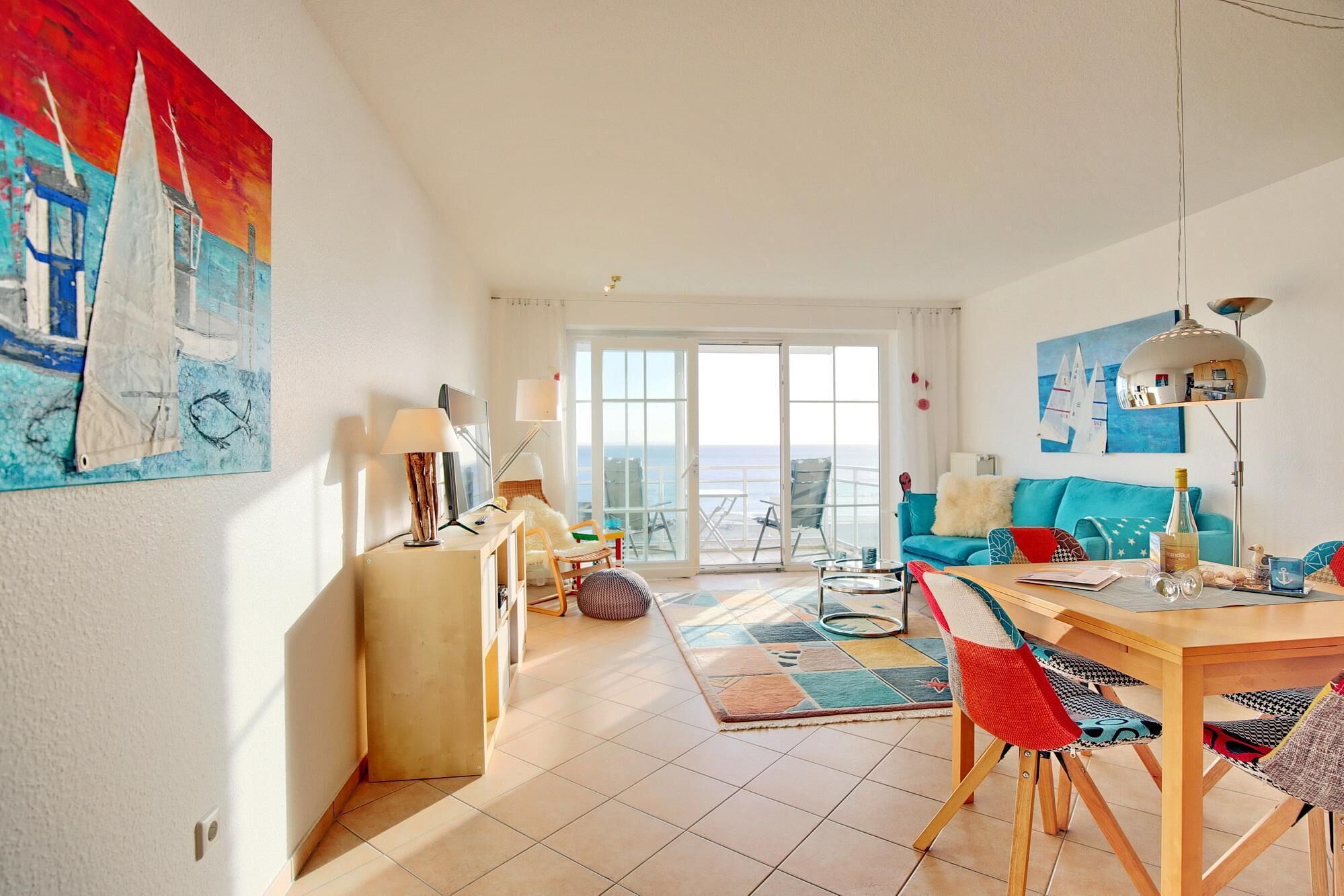 A spacious living area with a large window, a dining table, and a sofa.