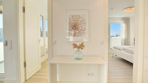 A hotel room with a white console table, a framed artwork above it, and a vase with dried flowers. - Villa Seeperle II Herzmuschel Appartement 18 (Scharbeutz)
