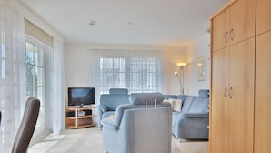 A modern living room with a sofa set, a television, and a wooden cabinet.
