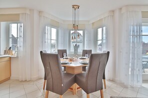 Un espace repas comprenant une grande table, quatre chaises et un luminaire suspendu.