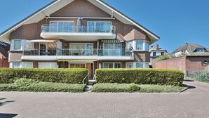 A two-story house with a balcony on the upper floor, a garage, and a well-maintained hedge in front. - Seesternresidenz Appartement 16 (Scharbeutz)