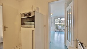 A kitchen with a built-in microwave and oven, a door leading to a balcony with outdoor furniture. - Seesternresidenz Appartement 16 (Scharbeutz)