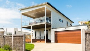 Una casa moderna de dos pisos con balcón, garaje y césped cuidado.