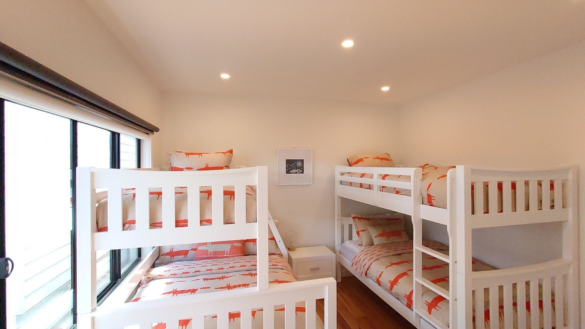 A room with bunk beds, a window, and a framed picture on the wall.