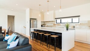 Una cocina moderna con una isla central, taburetes de bar e iluminación colgante.