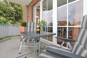 A patio with a table and chairs, a bottle of champagne, and a vase with flowers.
