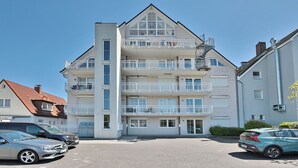Un immeuble résidentiel à plusieurs étages, doté de balcons, d’un garage et d’un espace de stationnement.