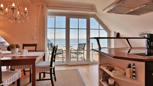 Une cuisine moderne avec vue sur la mer, un coin repas avec une table et des chaises, et une grande fenêtre.
