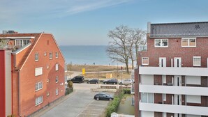 Ett bostadsområde med en byggnad i rött tegel, en vit byggnad med balkonger och utsikt över havet.