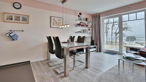 Ett modernt matområde med ett glasbord, svarta stolar och utsikt över omgivningen genom stora fönster.
