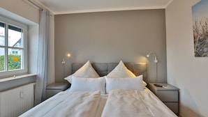 Un lit bien fait, avec du linge de lit blanc, deux tables de chevet avec des lampes et une fenêtre avec des rideaux.