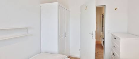 Un dormitorio con dos camas, un armario y un aparador.
